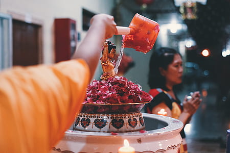 photo of person pouring water on deity figurine thumbnail