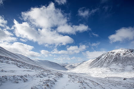 snow-covered mountain and field under cloudy blue sky thumbnail