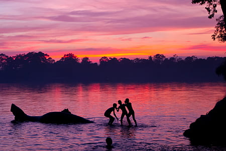 silhouette of four persons on body of water at golden hour thumbnail