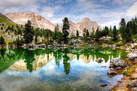 trees and mountain reflecting on body of water photo thumbnail