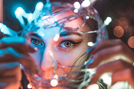 woman holding white string lights while taking self thumbnail