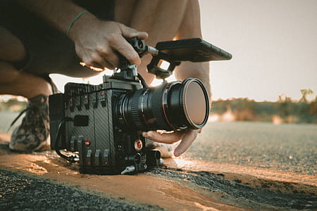person holding black multimedia camera on asphalt road during daytime thumbnail