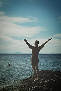 man standing on stone near water during daytime thumbnail