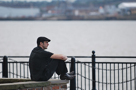 macro photography of man sitting beside water thumbnail