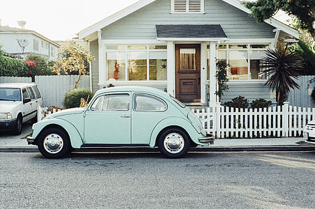 teal Volkswagen Beetle near white wooden house thumbnail