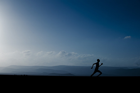 silhouette of man sprinting under blue clouds thumbnail