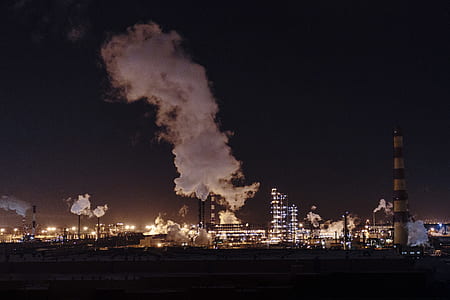 brown and beige concrete factory produces smokes at nighttime thumbnail