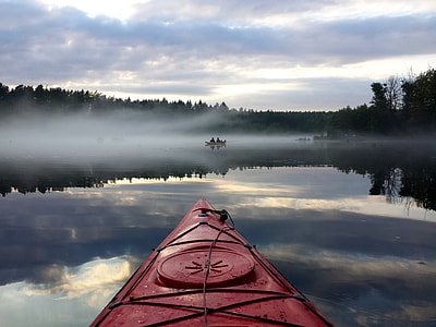 people riding boat on body of water under cloudy sky thumbnail