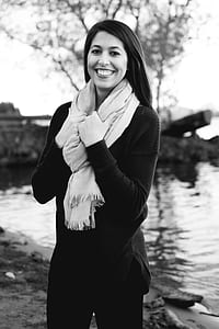 Grayscale Photography of a Woman Wearing Sweatshirt and Black Pants While Holding Scarf thumbnail