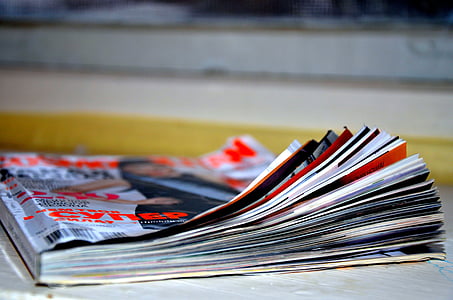 selective focus photography of gray and red magazine on white wooden surface thumbnail