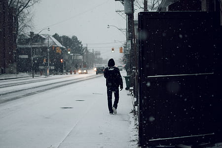 man walks on snow covered road thumbnail