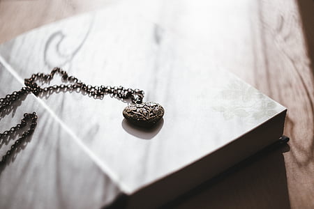 heart-shaped silver-colored pendant necklace on table thumbnail