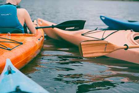 person wearing black vest riding on kayak with paddle thumbnail