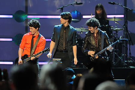 four men band performing on stage thumbnail