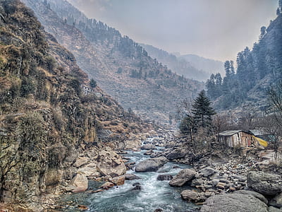 river in between mountain, house and trees at daytime thumbnail