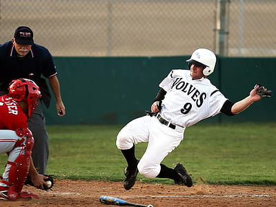 Male Baseball Player in Wolves 9 Jersey Sliding in Front of Male in Catchers Uniform Holding Baseball on Brown Mitt thumbnail