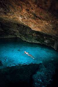 woman swimming on body of water inside cave thumbnail