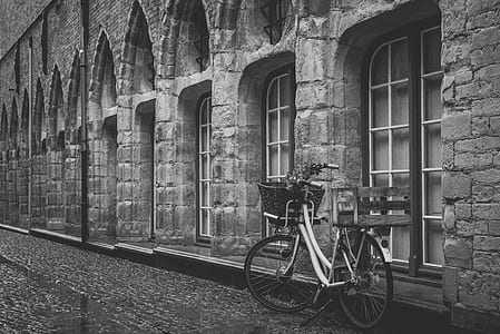 grayscale photography of bicycle parked near concrete building thumbnail