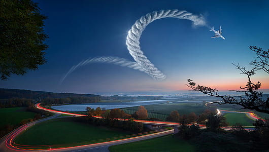 green field, gray road and white plane in time lapse photography thumbnail