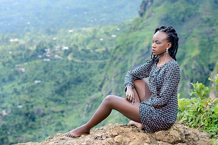 Woman Sitting on Ground Near Mountain thumbnail