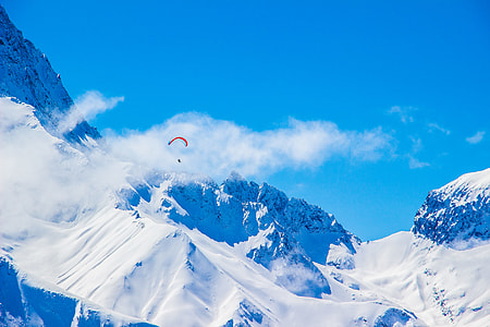 person paragliding over snow covered mountain thumbnail