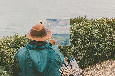 man doing painting near green leaf plant during daytime thumbnail