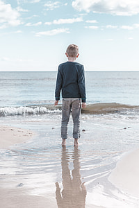 boy wearing black sweater on sea shore thumbnail
