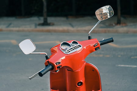 orange motor scooter parked on road side thumbnail
