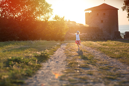 woman in white and red clothes raising two hands while running on greenfield side pathway reflected sun by sun during daytime thumbnail