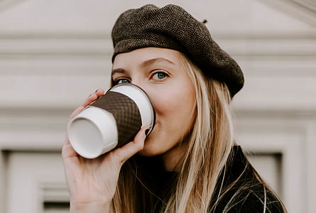 selective focus photography woman in black cap and black top drinking thumbnail