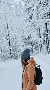 woman standing on snow field near trees thumbnail