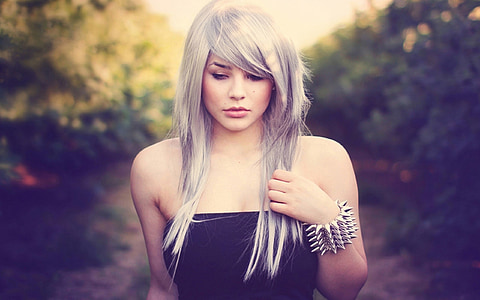 woman with gray dyed hair walking in between trees under shade of tree during daytime thumbnail