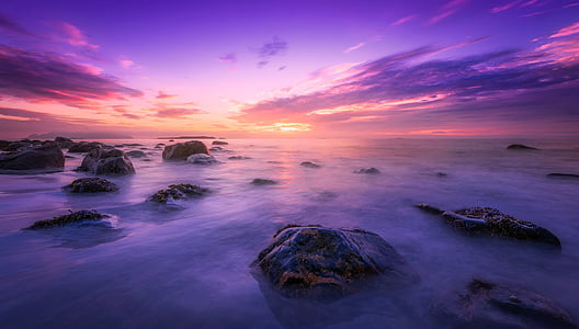 photo of black rocks in ocean during golden hour thumbnail