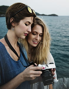 woman holding DSLR camera beside woman looking on camera thumbnail