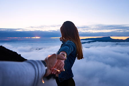man holding woman's hand on top of mountain thumbnail