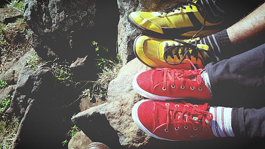 two person wearing yellow and red sneakers sitting on rock thumbnail