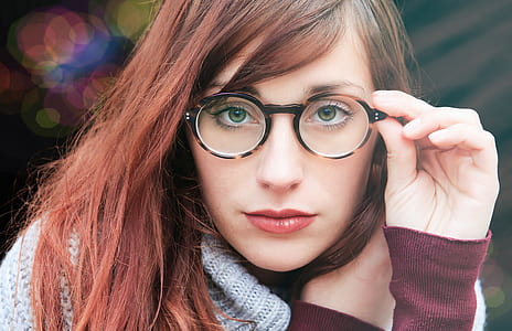 woman holding eyeglasses with black frames thumbnail
