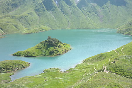 body of water surround by green mountains during daytime thumbnail