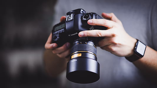 person holding Canon DSLR camera thumbnail