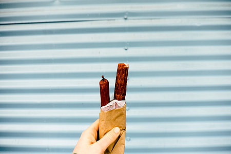 person holding paper bag with hotdogs thumbnail