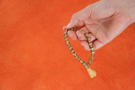 person holding beaded brown prayer beads thumbnail