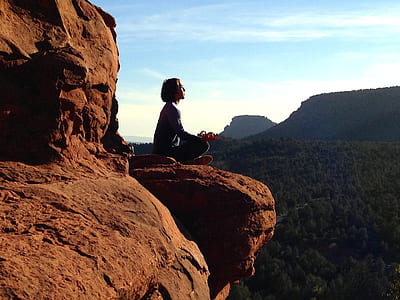 person meditating on brown rock formation thumbnail