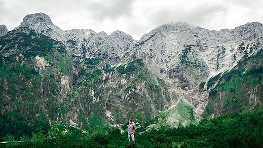 man standing on green grass with mountain in background thumbnail