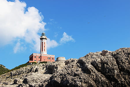 brown and white lighthouse on brown cliff during daytime thumbnail