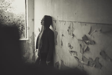 greyscale photo of woman leaning on wall during daytime thumbnail