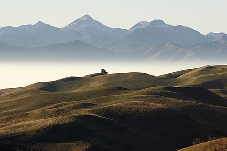 brown hills near mountains surrounded by fogs thumbnail