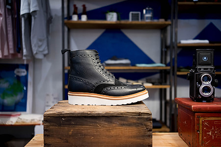unpaired black leather shoe beside vintage camera thumbnail