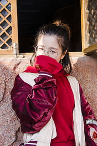 woman wearing white and red jacket standing beside window thumbnail