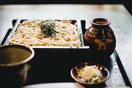 pasta in square green bowl beside brown ceramic container thumbnail