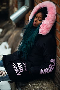 Woman Wearing Black and Pink Coat Leaning on Wall thumbnail